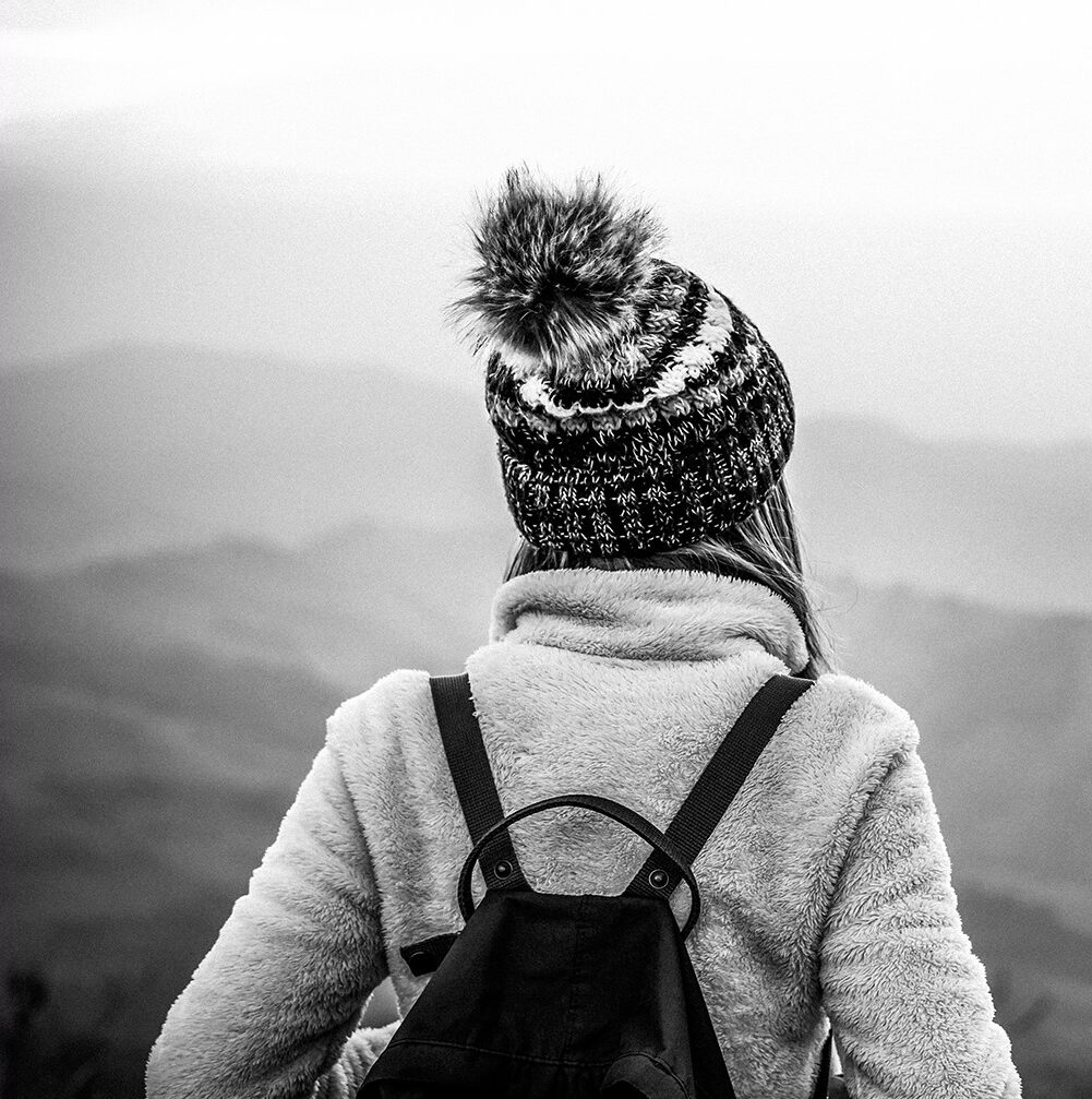 Black and white photo of a woman looking at mountain scenery - Mastering Alchemy